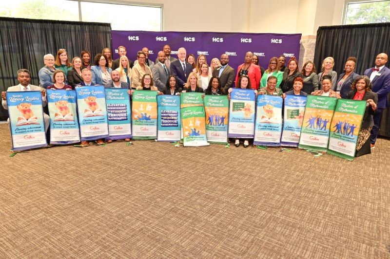 State School Superintendent, HCS leaders & 14 HCS principals holding Literacy & Math Leader banners